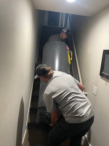Two Utah Water Heaters Now technicians carrying an old 50-gallon water heater down a staircase